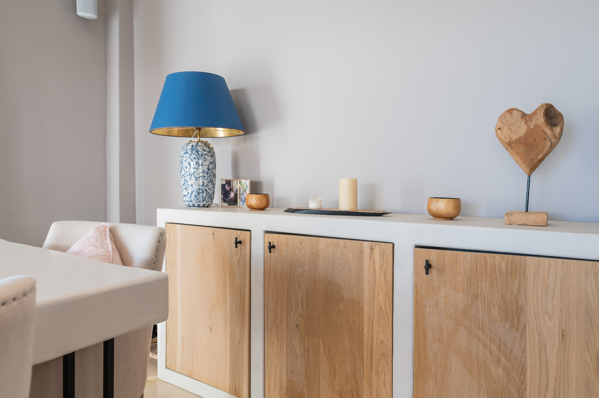 Detail van wit dressoir met houten deurtjes en blauwe lamp