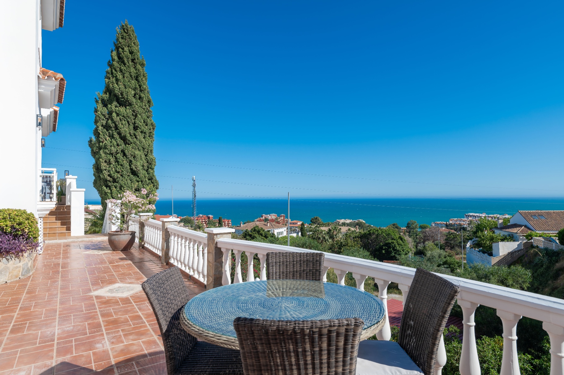 Terras met ronde tafel, cipres en open uitzicht op zee