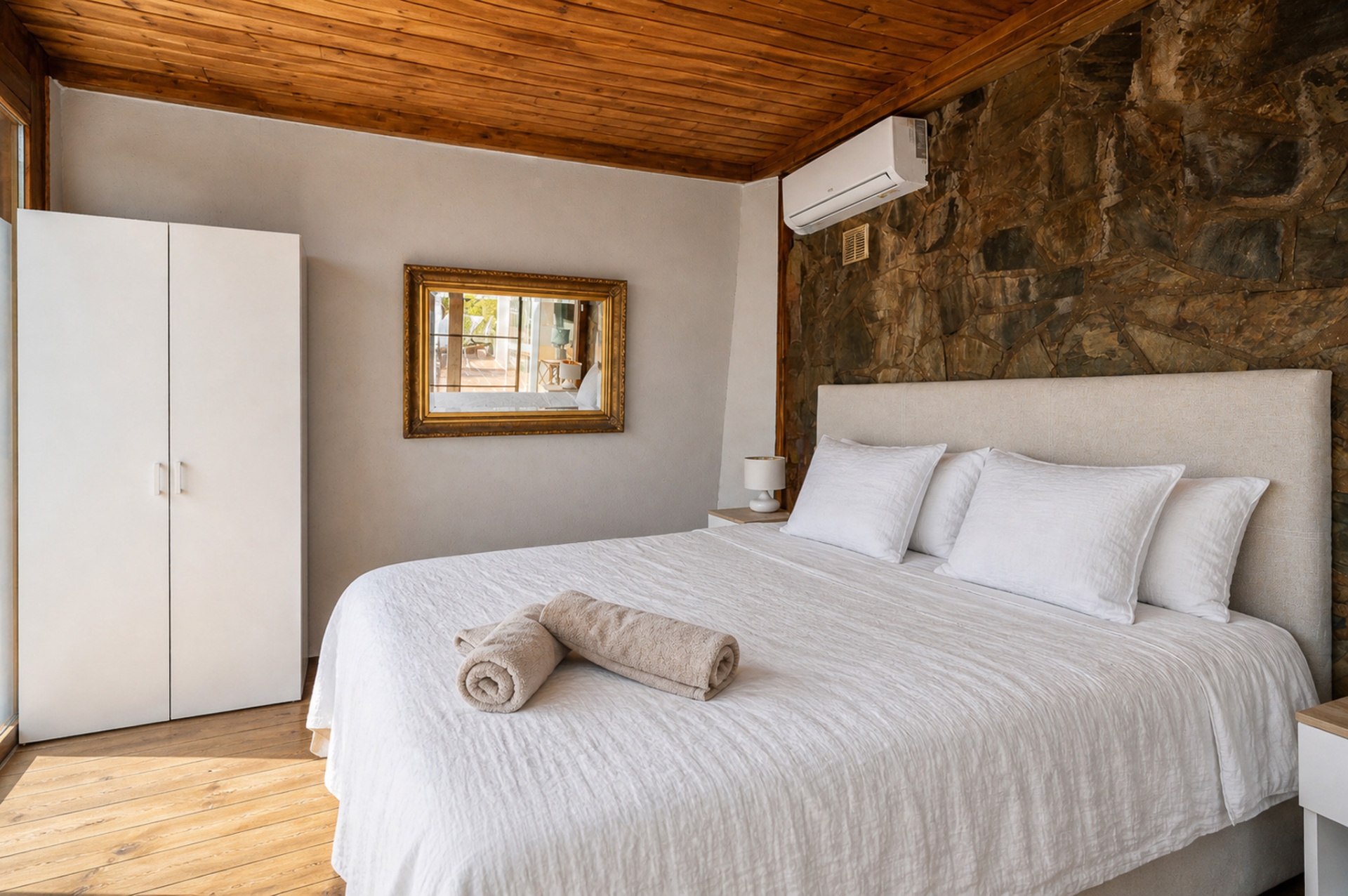 Slaapkamer 4 met houten plafond, natuurstenen wand en linnen hoofdbord