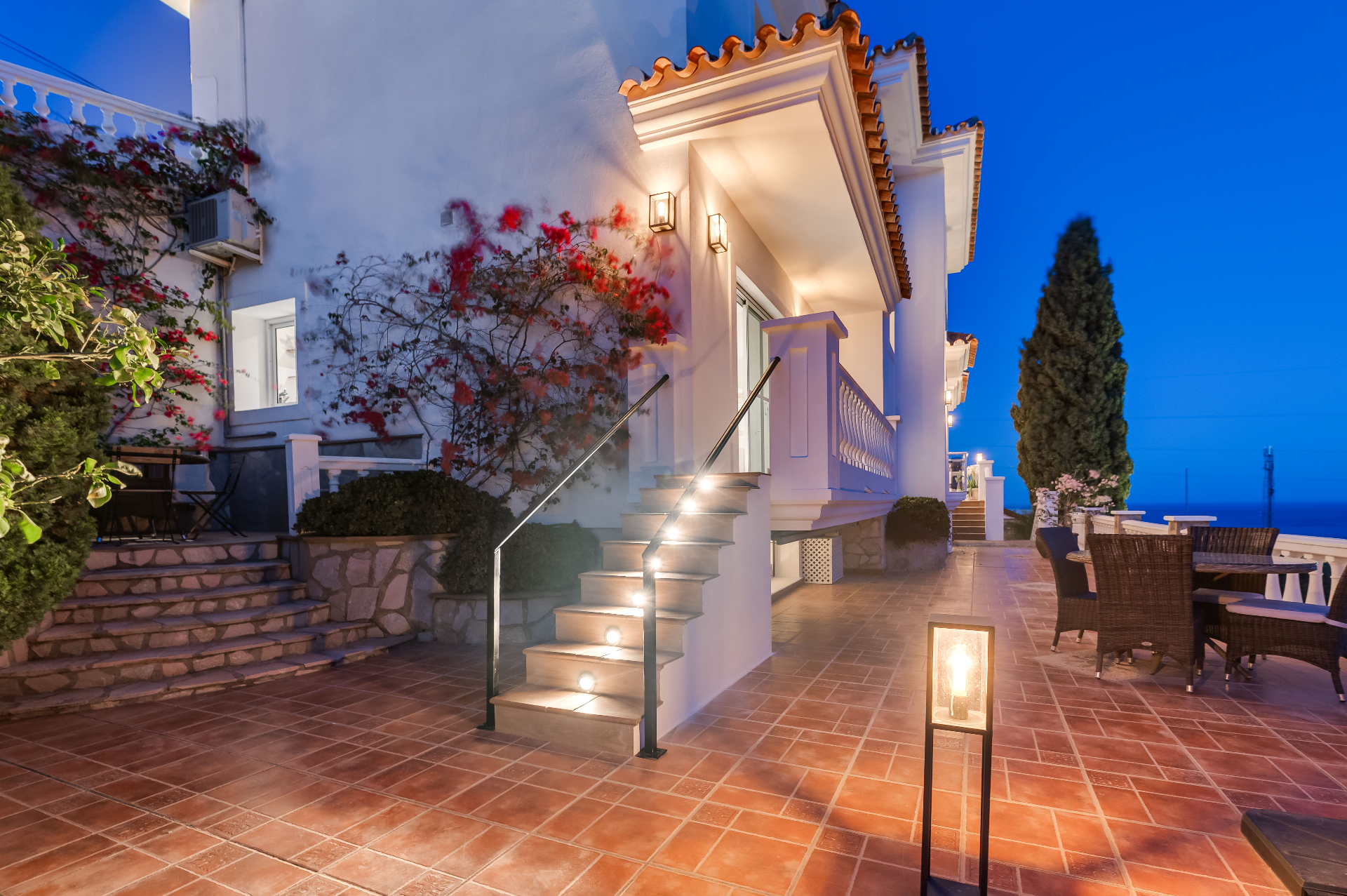 Avondterras met verlichte trap, bougainville en eettafel buiten