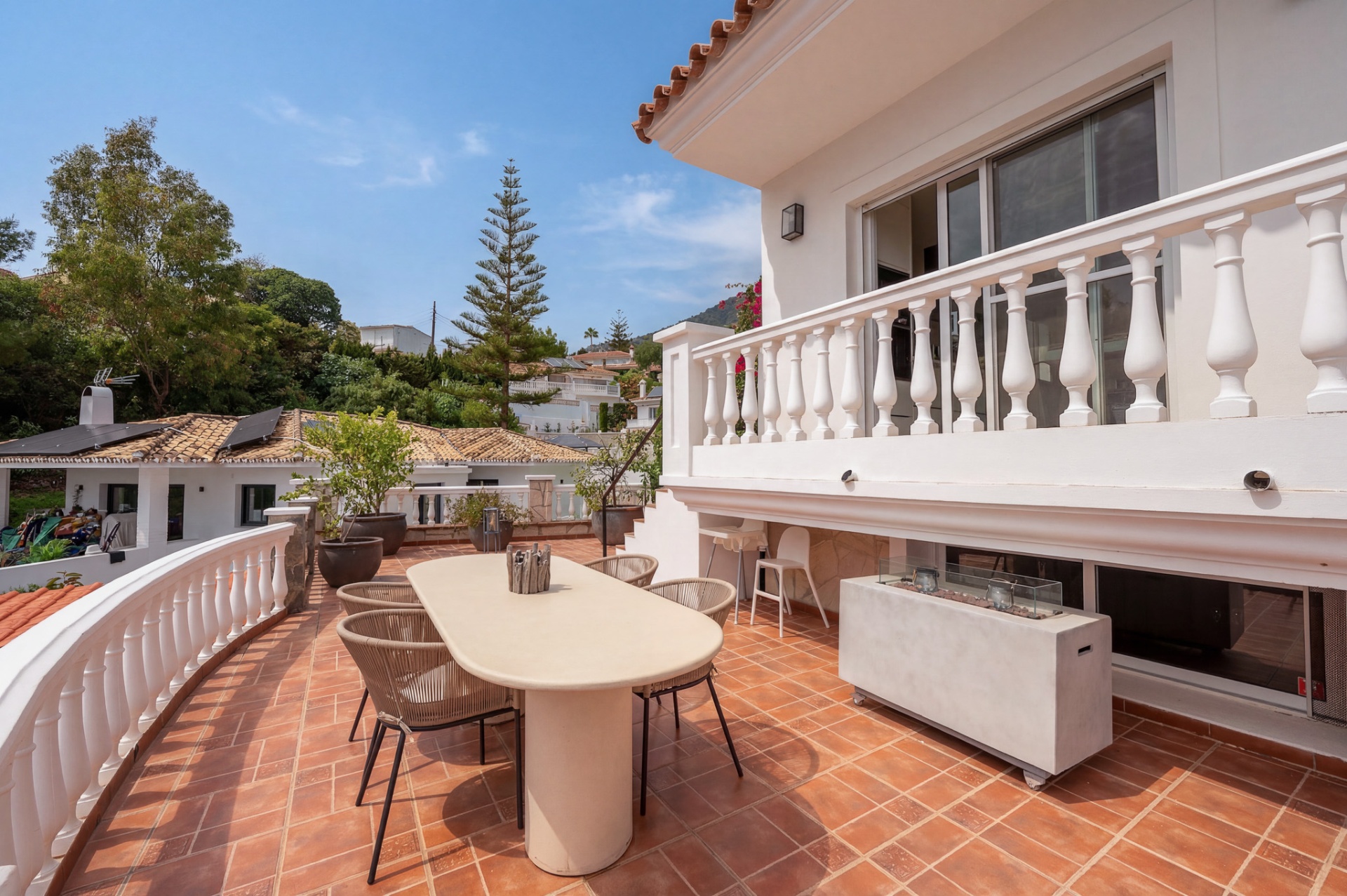 Terras met eettafel, moderne vuurtafel en gebogen balustrade