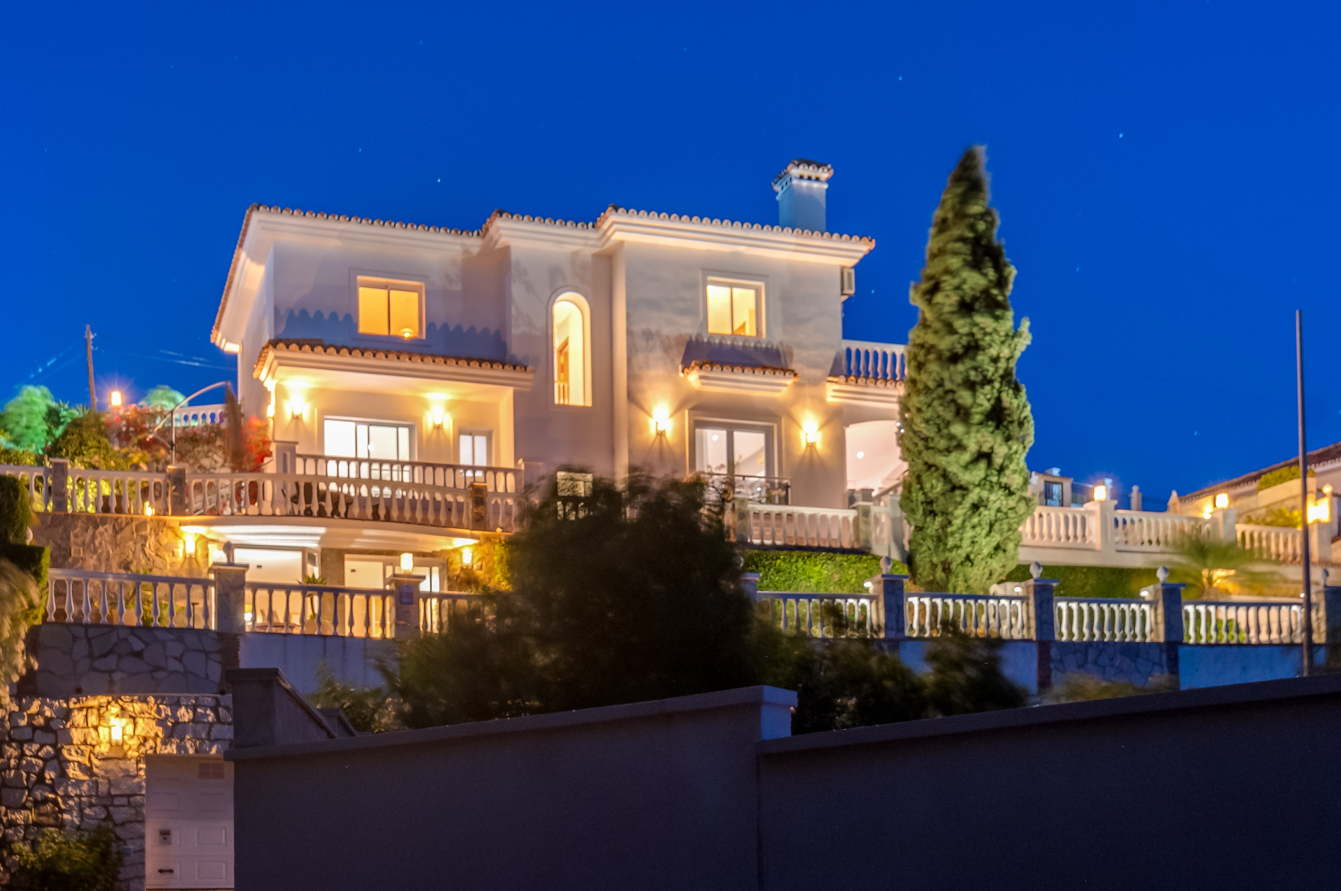 Wijds avondzicht op de villa met verlichte terrassen en balustrades