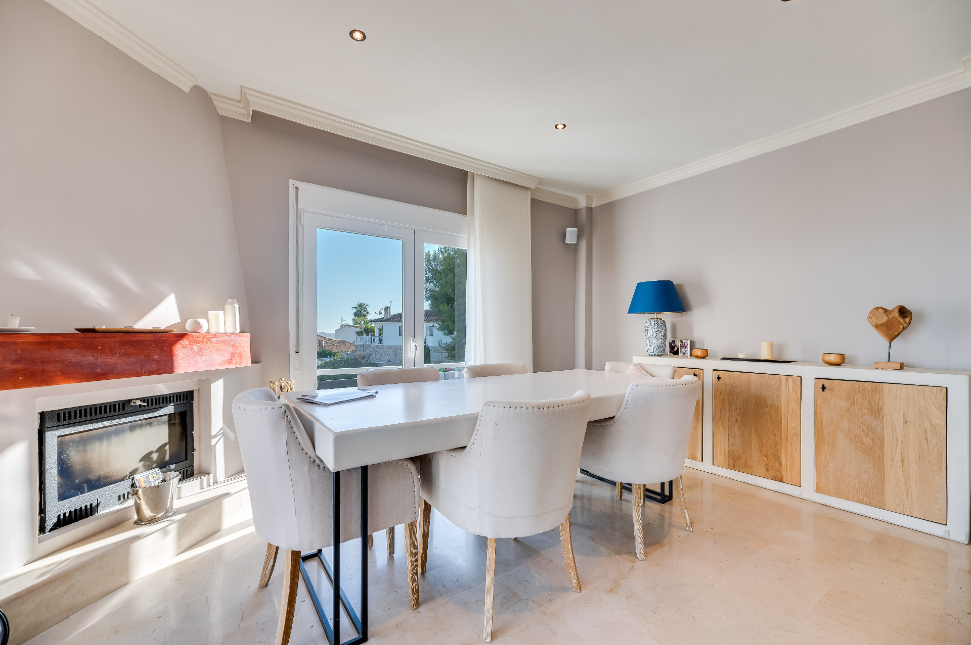 Eetkamer met lichte fauteuils, houten dressoir en zacht daglicht